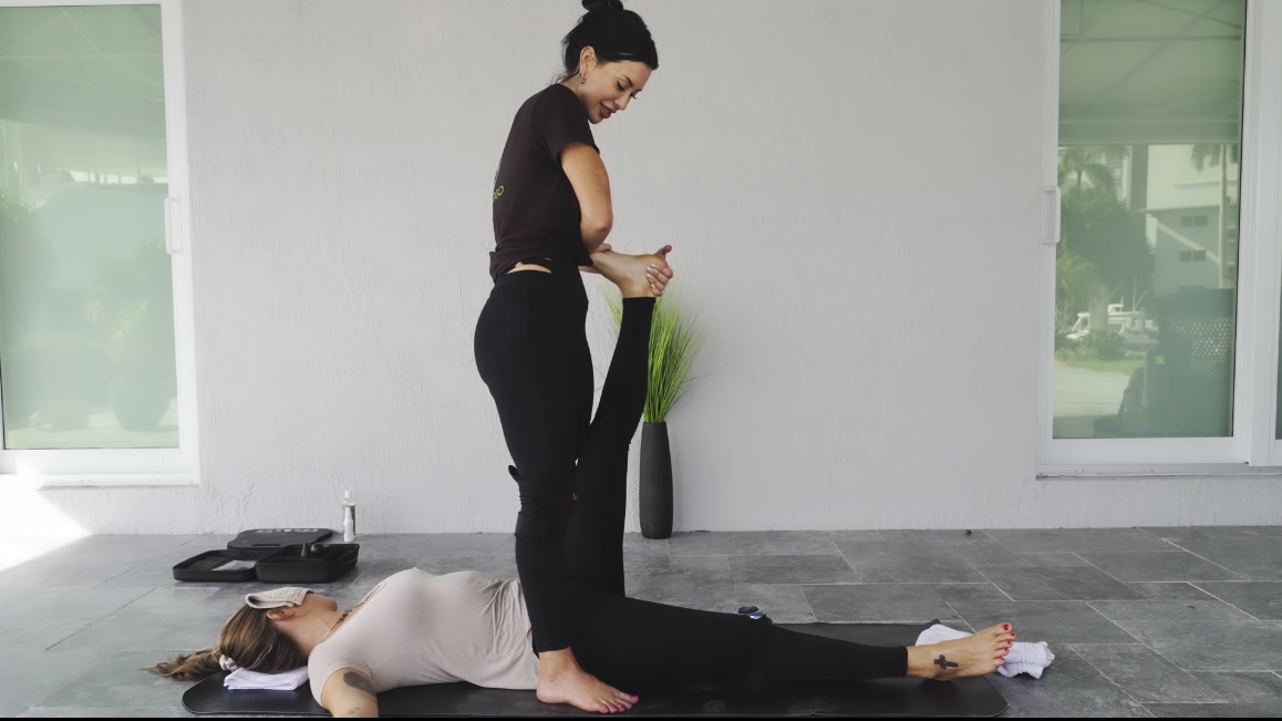 A Stretchtogo practitioner performing an assisted stretch on a client